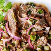 Nuer Nam Tok (Waterfall Beef) · Grilled sliced steak cooked with roasted rice, red onions, scallions, cilantro and lime juice.