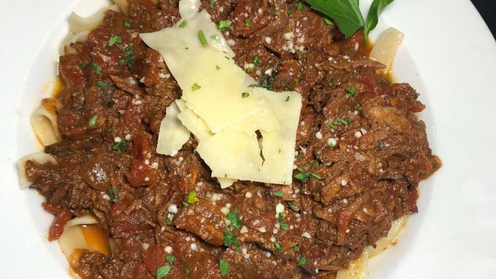 Braised Beef Over Pasta · Tender all-natural beef, braised with carrots, celery & onions. Simmered for hours in Burgundy wine & fresh beef stock reduction. Served over a bed of homemade pappardelle pasta and finished with grated Romano cheese