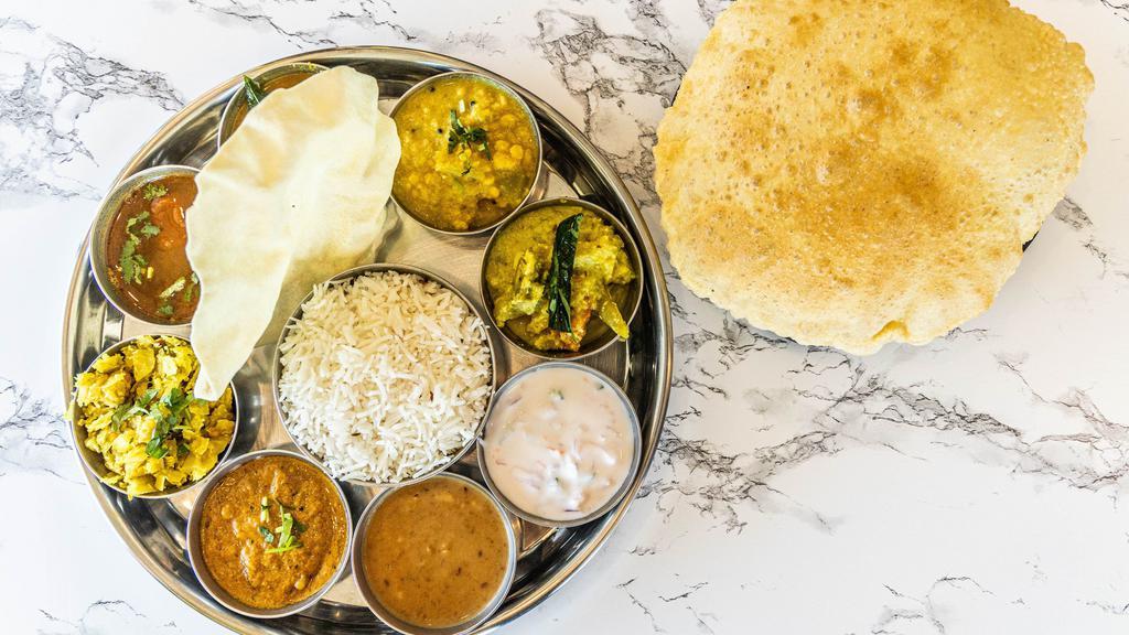 Veg Thali · An assorted platter thali of poriyal, avial, sambar, rasam, kottu, vegetable of the day, dal, yoghurt, pickle, papad, dessert served with rice and roti.