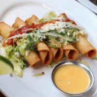 Taquitos Chicken Appetizer · Five crispy corn tortillas rolled with hand-pulled chicken. Topped with red chile sauce, shr...