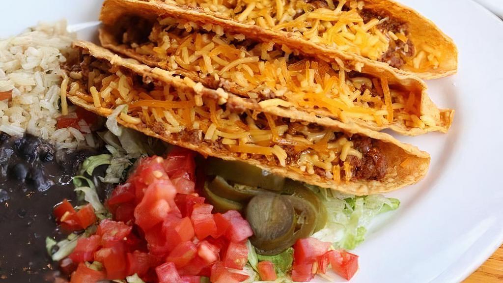 Tacos Crispy · Three crispy corn tortilla shells with seasoned ground beef, lettuce, cheddar cheese, tomato and pickled jalapeño. Served with green chile rice & refried beans (or substitute mashed black beans.). Can be prepared Gluten Free upon Request.  Online Orders select the Make it GF! modifier.