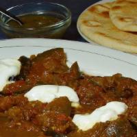 Eggplant Bouranee · Cooked in spiced tomato sauce, with yogurt and roti.