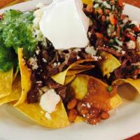 Azteca Nachos · Loaded nachos topped with choice of meat chicken, steak, or beef, refried beans, lettuce, fr...