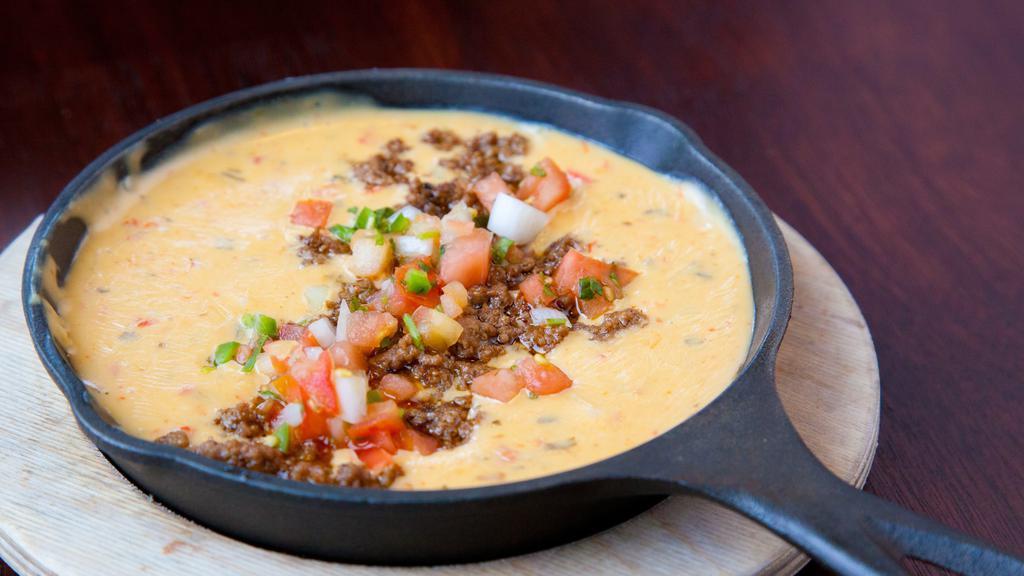 Skillet Beef Queso · Our white queso with ground beef and pico de gallo and chips.