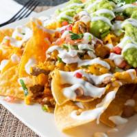 Nachos De Carne Enchilada / Spicy Meat Nachos  · served w/beans, onions, tomatoes, sour cream, cheese, jalapeño, and guacamole.