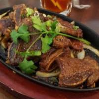 Bbq Short Ribs · Marinated sliced beef on a bed of caramelized onions. Served on a hot plate.