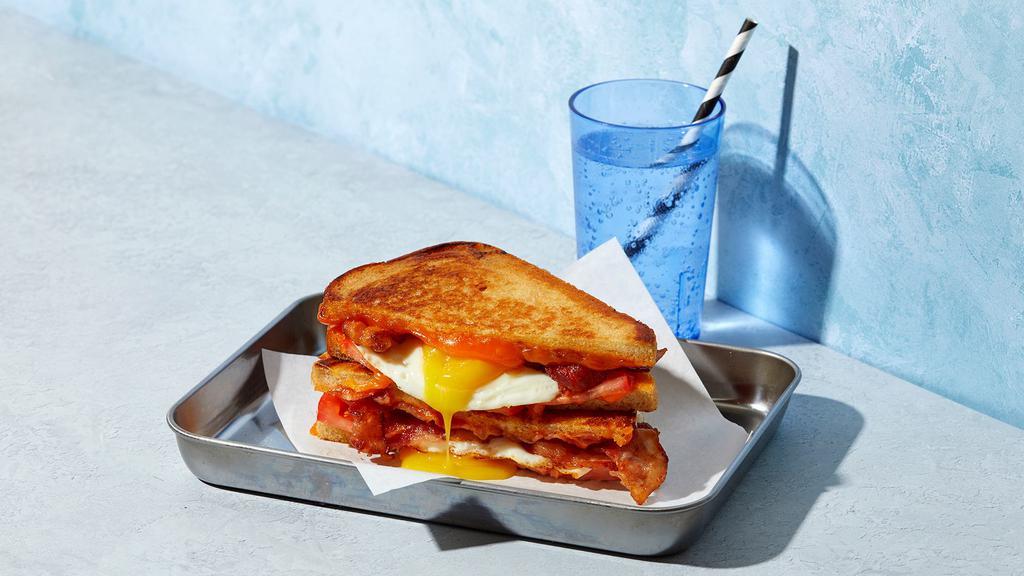 The Bacon Breakfast · Melted Cheddar cheese with a fried egg, tomato and bacon strips grilled between two slices of buttered bread.