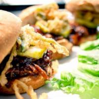 Brisket Sliders · Three sliders topped with BBQ brisket, a pickle slice and fried jalapeño onion strings.
