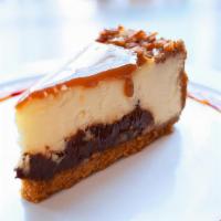 Turtle Cheesecake · Caramel sauce and chopped pecans sit atop layers of cheesecake and dark fudge, all on a grah...