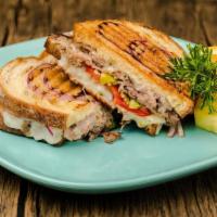 Roast Beef And Garlic Panini · Savory, tender roast beef, stacked on red bell peppers, red onion, and pepperoncini topped w...