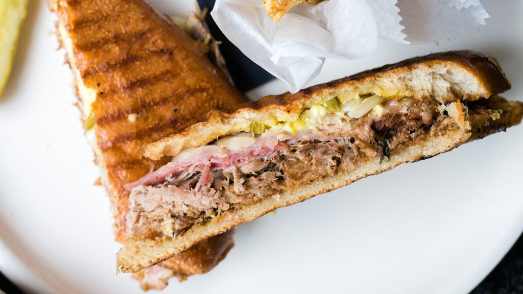 Cubano Sandwich · Slow-roasted pork shouLder, hoagie roll, swiss cheese, prosciutto, pickled jalapeños & onions, garlic aioli. Served with a house pickle spear and choice of mixed greens, French fries, or soup.