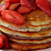 Strawberry Pancakes · Two large strawberry buttermilk pancakes with butter and syrup.