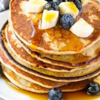 Blueberry Banana Pancakes · Two large buttermilk pancakes with blueberry, bananas, syrup and butter.
