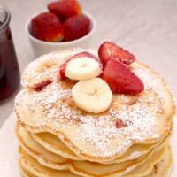 Strawberry Banana Pancakes · Two large buttermilk pancakes with bananas and strawberries, butter and syrup.