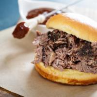 Smoked Brisket Sandwich · Thick and tender smoked Brisket, sliced thick on a brioche roll, topped with Au jus, caramel...