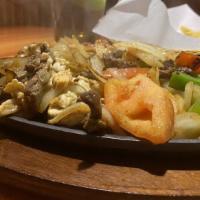 Fajitas Texanas · Grilled shrimp, chicken and steak cooked with peppers, onions and tomatoes. Served with lett...