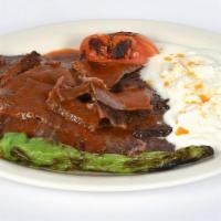Iskender Kebab · Thinly sliced doner meat served with chopped pita bread, yogurt and tomato sauce on top.