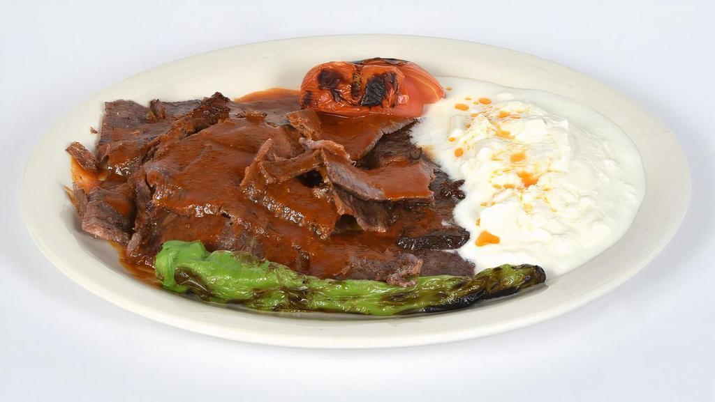 Iskender Kebab · Thinly sliced doner meat served with chopped pita bread, yogurt and tomato sauce on top.