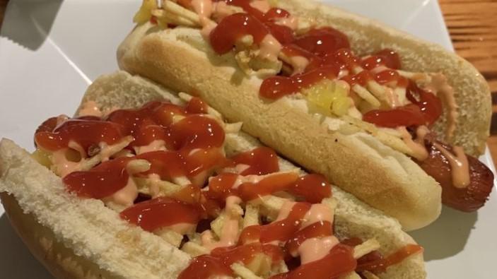 Colombian Hotdog · Hot dog topped with bacon, ham, cheese, pineapple, crushed potato chips, pink sauce and ketchup.