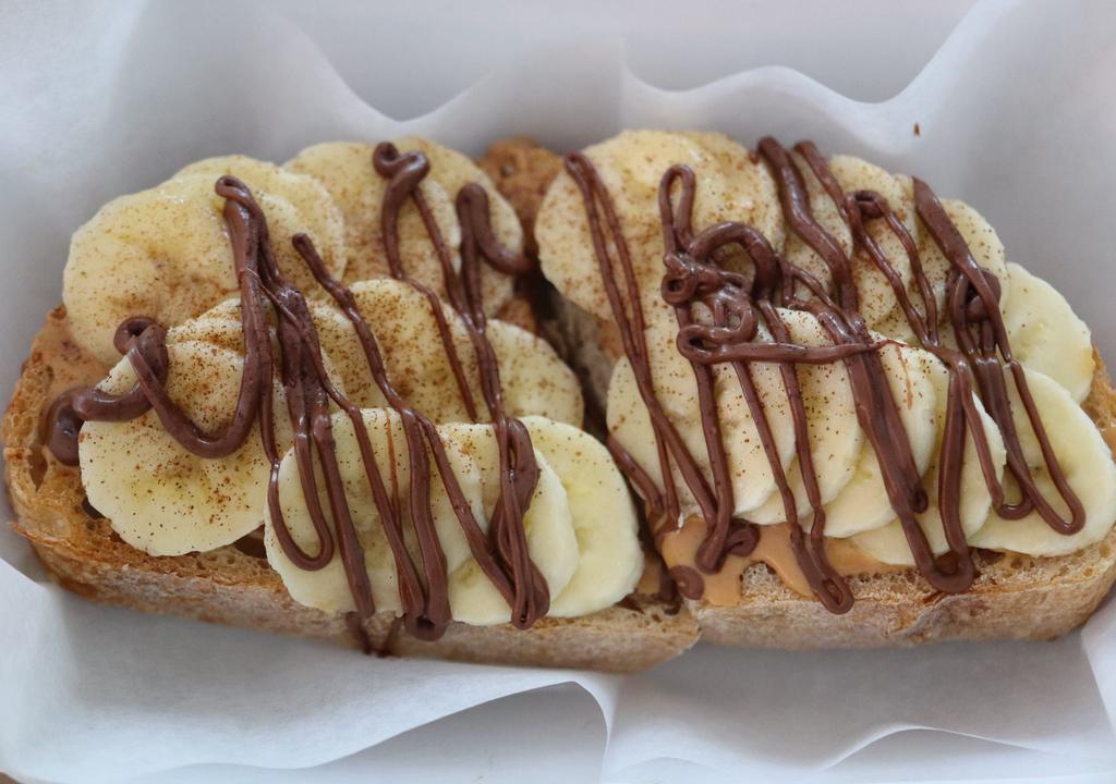 Nutella Peanut Butter Toast · Local sourdough toast with peanut butter, banana, hemp seeds and cinnamon. Drizzled with Nutella & honey