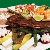 Costillas De Res · Beef ribs served with rice, beans and salad.