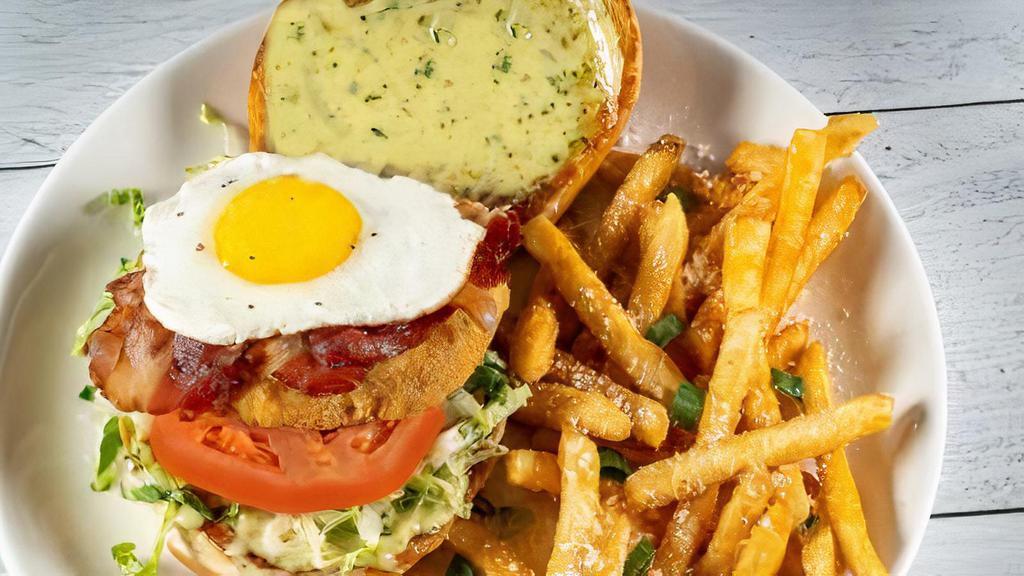 Crispy Chicken Bacon + Egg · Crispy fried chicken layered w/shredded lettuce, vine ripened tomato, hickory-smoked bacon + a cracked-fresh, over-light egg, served on a toasted brioche roll w/pesto-garlic aioli + a side of seasoned french fries.