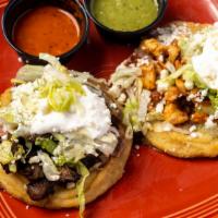 Sopes ( 3 ) · Three round and flat pieces of corn dough with steak or chicken topped with beans, lettuce, ...