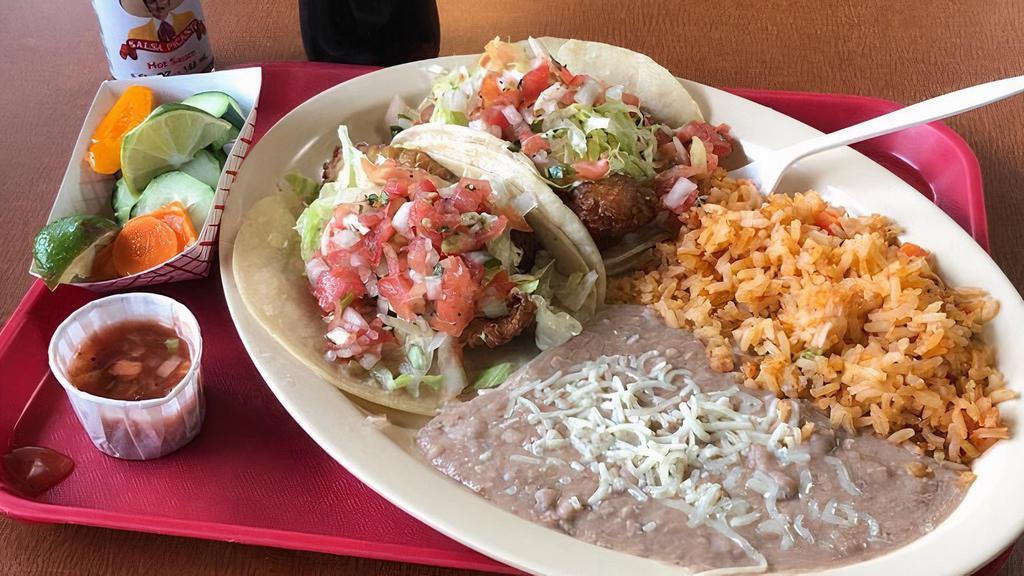 2 Fish Tacos (White Fish) · Two battered fish tacos on corn tortilla topped with Tatar sauce ,lettuce and pico de gallo with rice and beans.