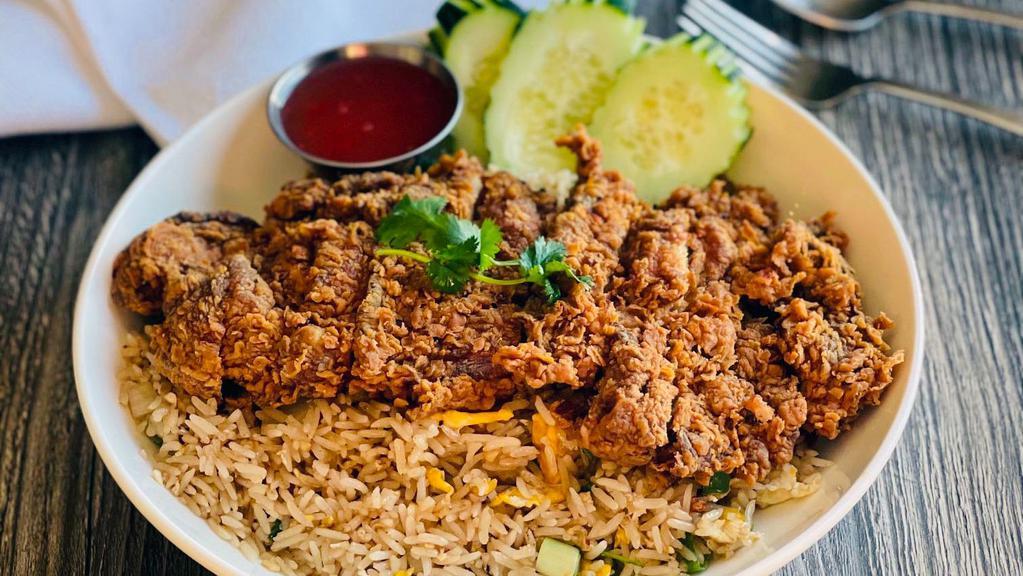 Kao Pad Gai Tod · Deep fried boneless chicken over fried rice with egg, garlic white onion and tomatoes. Topped with cilantro and cucumber and served with sweet and sour sauce.
