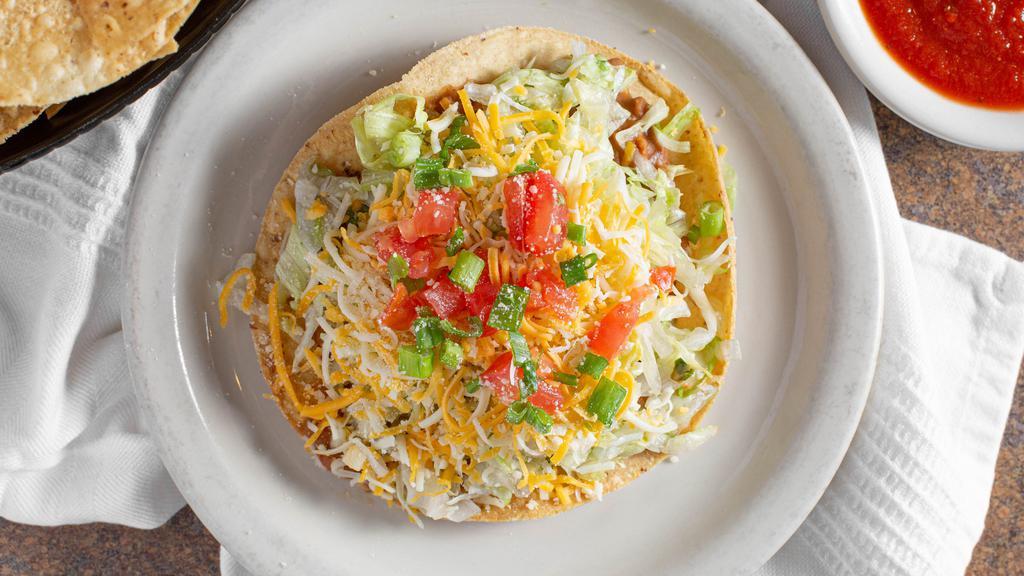 Tostada · Corn tortilla fried flat topped with beans, your choice of protein, lettuce, tomato, cheese, onion and parmesan cheese