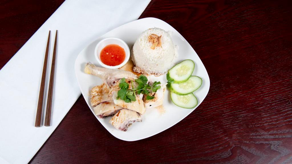 Hainanese Chicken Rice · Steamed chicken in bone with sweet soy sauce and special chili sauce served with chicken flavor rice and cucumber.