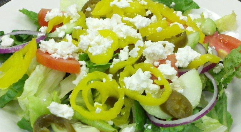 Greek Salad · A delightful blend of fresh mixed greens topped with red onions, black olives, tomatoes, jalapenos, banana peppers, and feta cheese.