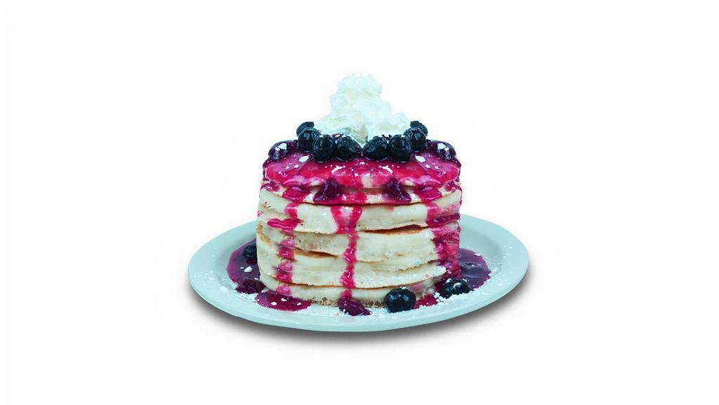 Berries Pancakes · Buttermilk pancakes filled with blueberries. Topped with blueberries, strawberry glaze, whipped cream and powdered sugar.
