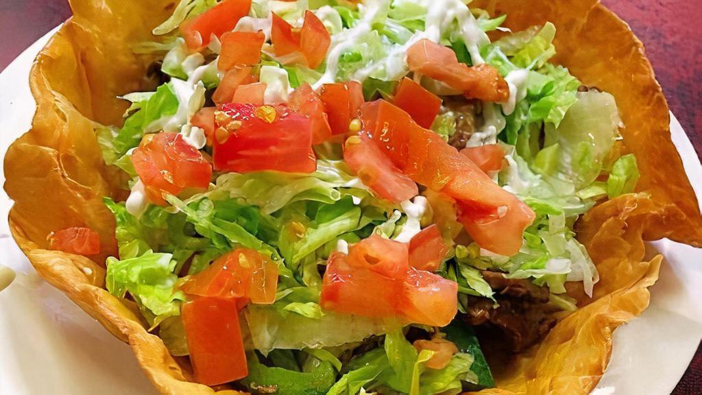 Fajita Taco Salad · Your choice of steak or grilled chicken, grilled onions and peppers, served on a crispy flour tortilla basket lined with refried beans, rice, lettuce, topped with delicious white cheese dip, sour cream, and guacamole.