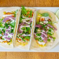 Grilled Shrimp Tacos · Spicy. Chili spiced, sweet corn tomalito, arugula, pickled onion, lime crema, fresh cilantro.