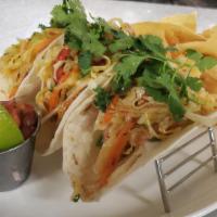 Baja Shrimp Tacos · Flour tortilla, guacamole, pico de gallo, cilantro slaw, crispy tortilla strips.