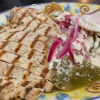Chilaquiles Rancheros · Tortilla chips simmered in a red guajillo or green sauce, crema, queso fresco, onions, and a...