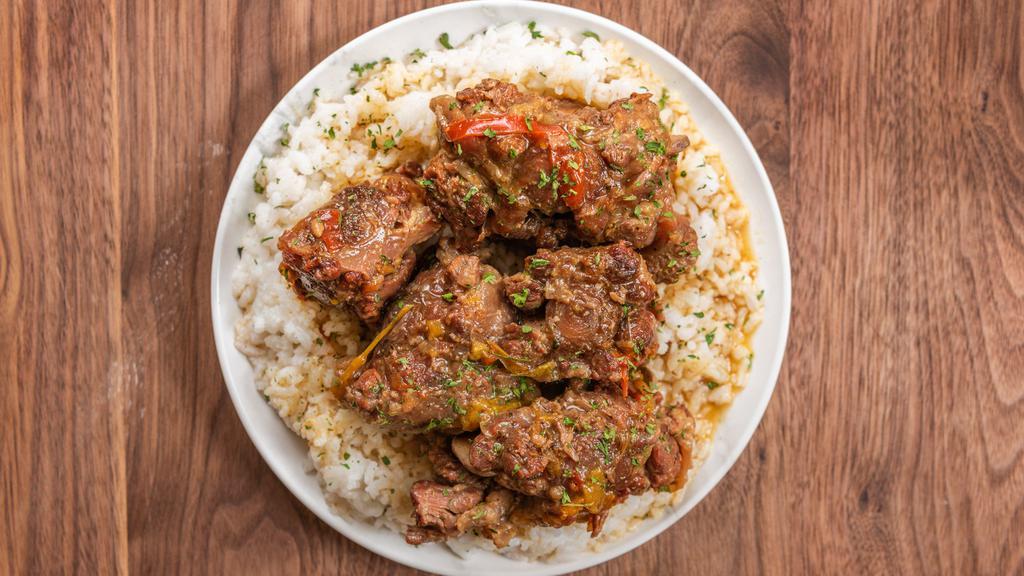 Oxtails · Tender fall off the bane oxtails over a bed of white rice and two sides.