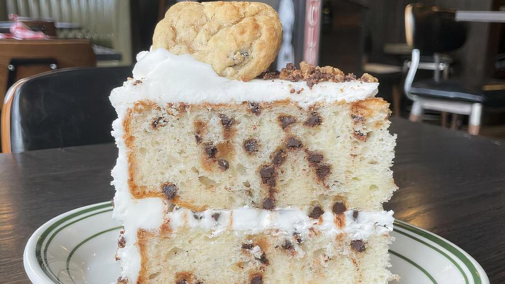 Chocolate Chip Cookie Cake · White cake with chocolate chips, iced with vanilla buttercream topped with chocolate chip cookies and garnished with chocolate chip cookie crumbles