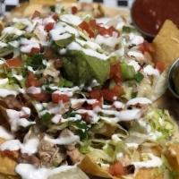 Chicken Nachos · House-made queso, grilled chicken, refried beans, lettuce, tomatoes, pickled jalapeños, guac...