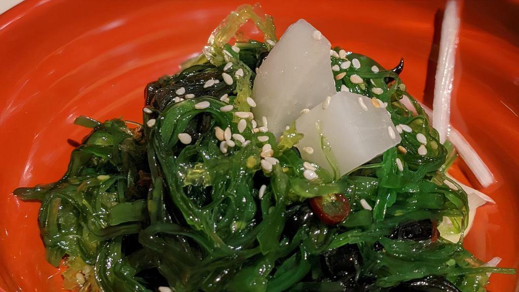Seaweed Salad · A small side of seaweed salad on a bed of crunchy green papaya, topped with pickled daikon radish cubes.
