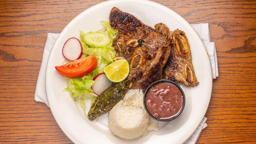 Costilla De Res · Deliciously marinated grilled beef short ribs served with rice, black beans, salad and a grilled jalapeño. Served with fresh handmade corn tortillas.