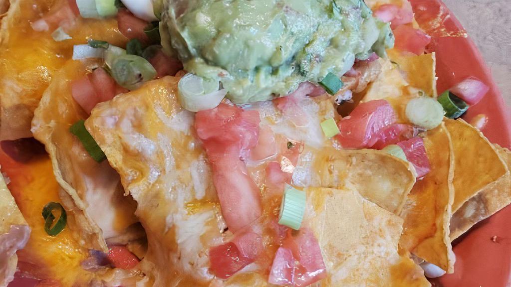 Nachos Fiesta · Crisp Corn Tortilla Chips Topped with Beans, Jalapenos and Melted Cheddar Cheese. Garnished with Tomatoes, Green Onions, Sour Cream, Pico De Gallo and Guacamole.
