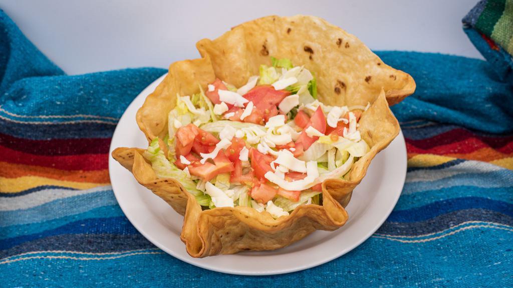 Taco Salad · Fried flour tortilla shell filled with refried beans, lettuce, cheese, sour cream, guacamole, and your choice of meat.