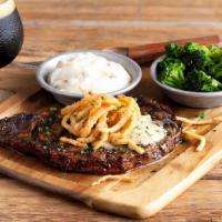 Ribeye* · 12 oz. USDA choice ribeye seasoned & grilled topped with stout butter & fried onions, served...