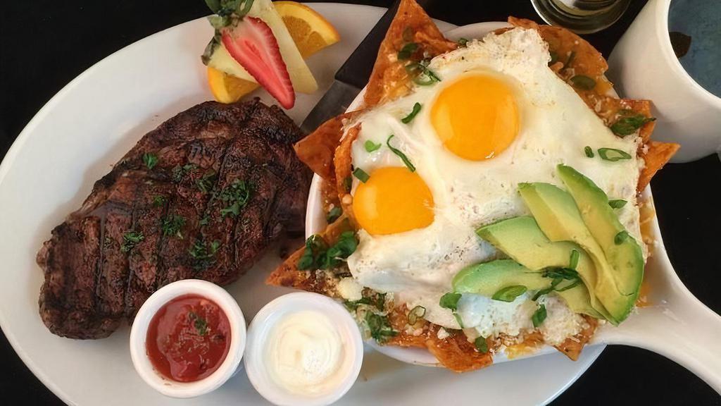 Spice-Rubbed Rib Eye Steak Chilaquiles · ribeye steak, ranchero chips, rojas sauce, refried beans, cheddar & cotija cheese, two eggs any-style, avocado, green onion, salsa & sour cream