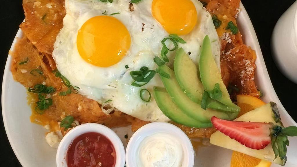 Pork Carnitas Chilaquiles · ranchero chips, vede sauce, refried bens, cheddar & cotija cheese, pork carnitas, two eggs any-style, avocado, green onion, salsa & sour cream.