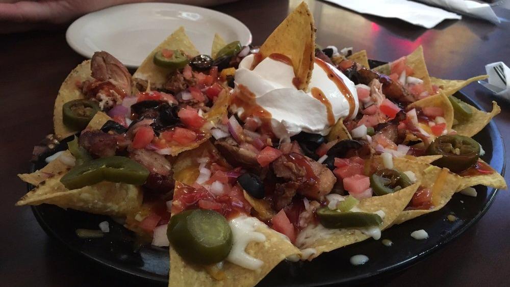 El Korn Nachos · Crispy corn chips topped with smoked shredded pork or chicken, cheddar and mozzarella cheeses, olives, jalapenos, onions, tomatoes and our special seasoned sour cream.