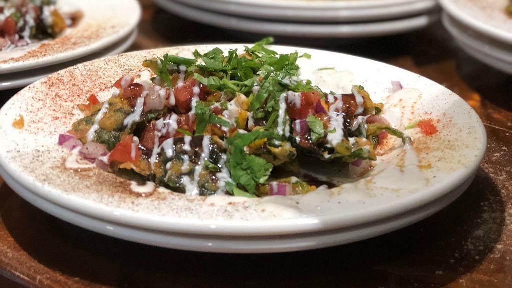 Aam Palak Chaat · Vegan, gluten free. Crispy fried spinach, served with IndAroma chat mix, diced mangoes, cilantro, sweet yogurt, mint, and tamarind sauces.