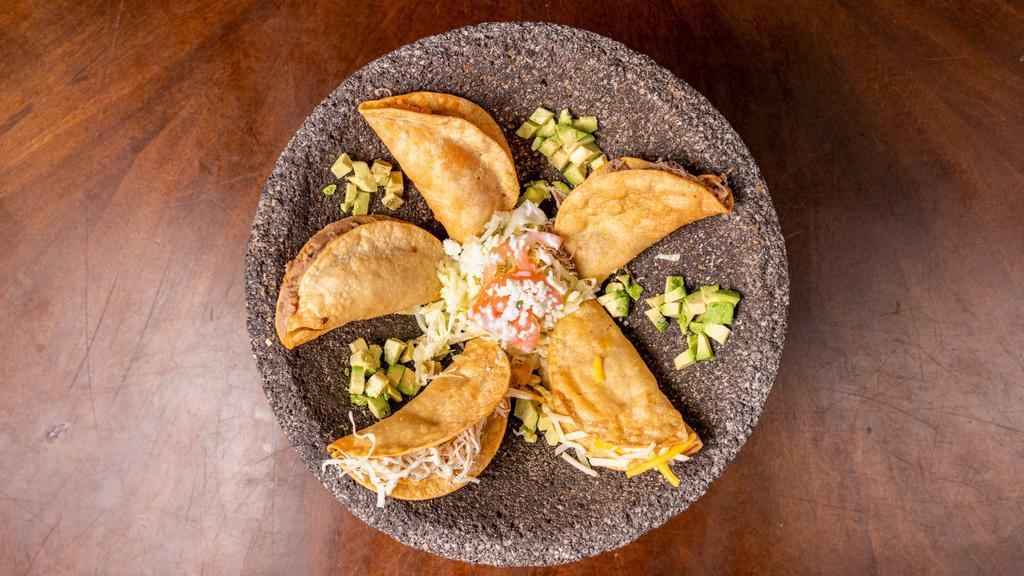 Tacos Dorados (Crispy) · 5 Corn tortillas filled with your choice of meat, then fried until nice and crispy, topped with lettuce, tomato, crema mexicana, avocado sauce and queso fresco.